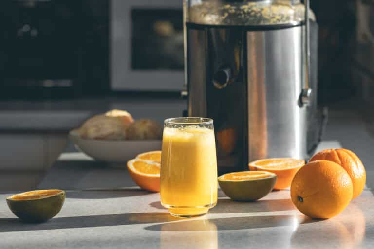 Frisch gepresster Orangensaft im Glas und Entsafter