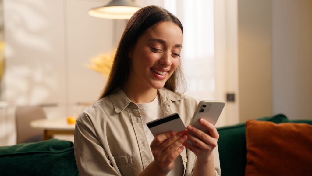 Junge Frau mit Smartphone und Bezahlkarte.