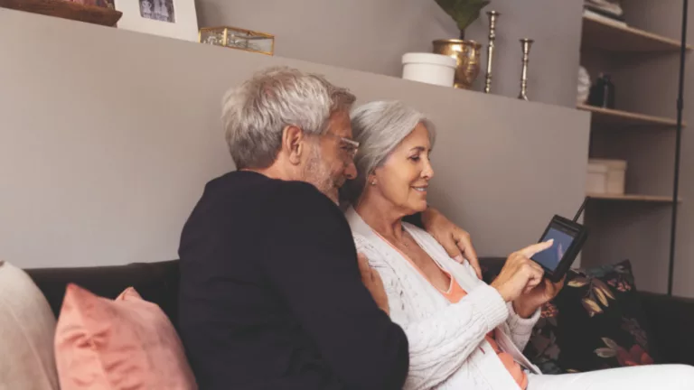 Zwei ältere Personen sitzen auf dem Sofa und schauen auf den Bildschirm des Easylook-Basicsets @Abus