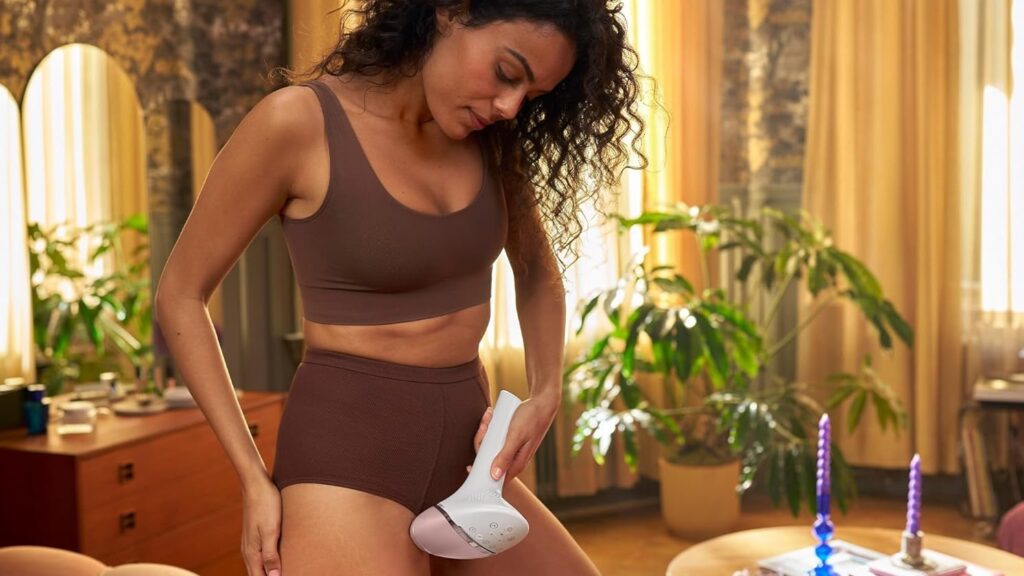 Frau lasert entlang des Oberschenkels mit einem Philips IPL-Gerät