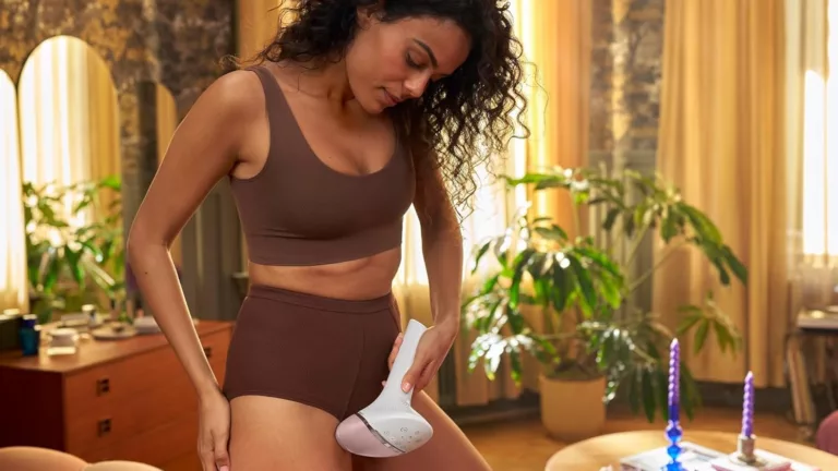 Frau lasert entlang des Oberschenkels mit einem Philips IPL-Gerät