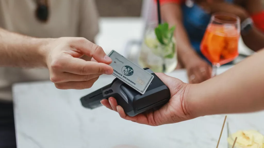 American Express Platinum Card wird vor ein Kartenlesegerät gehalten.