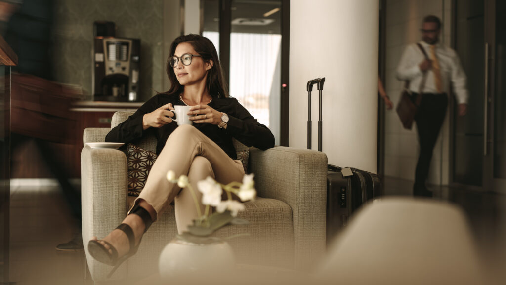 Businessfrau wartet am Flughafen mit Kaffeetasse in der Hand.