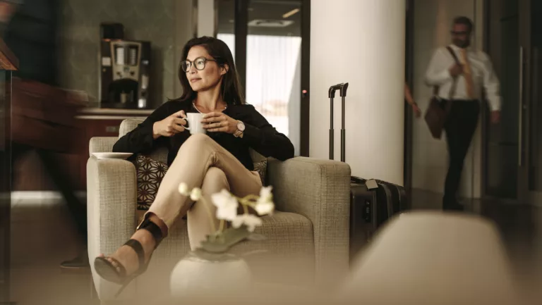 Businessfrau wartet am Flughafen mit Kaffeetasse in der Hand.