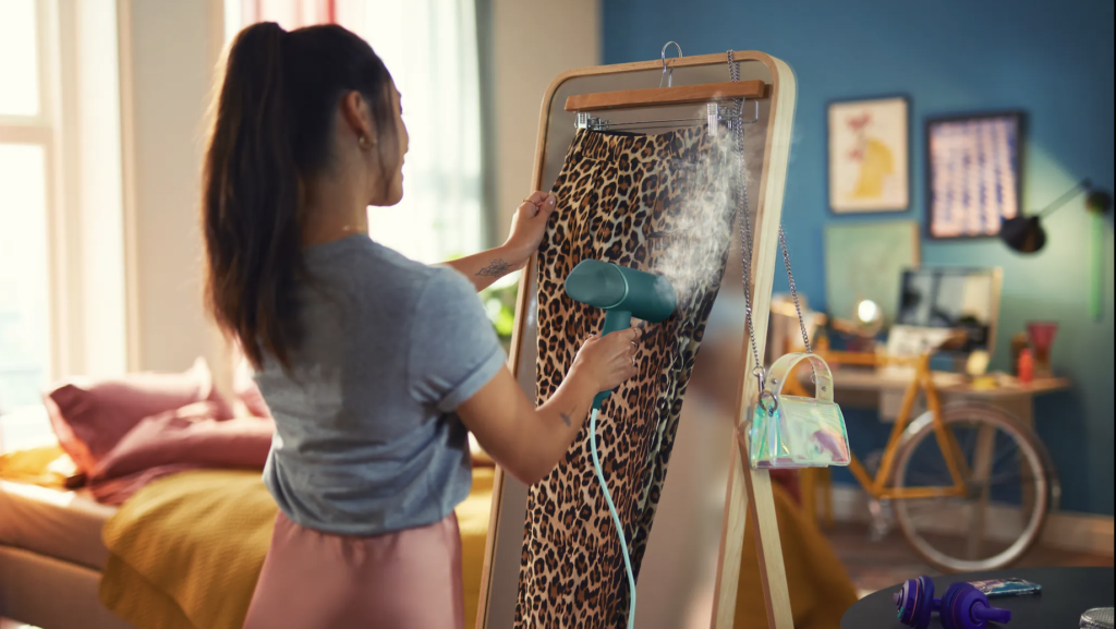 Junge Frau glättet einen Rock im Leoparden-Muster mit einem Steamer.