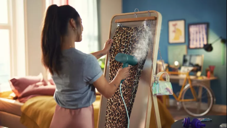 Junge Frau glättet einen Rock im Leoparden-Muster mit einem Steamer.