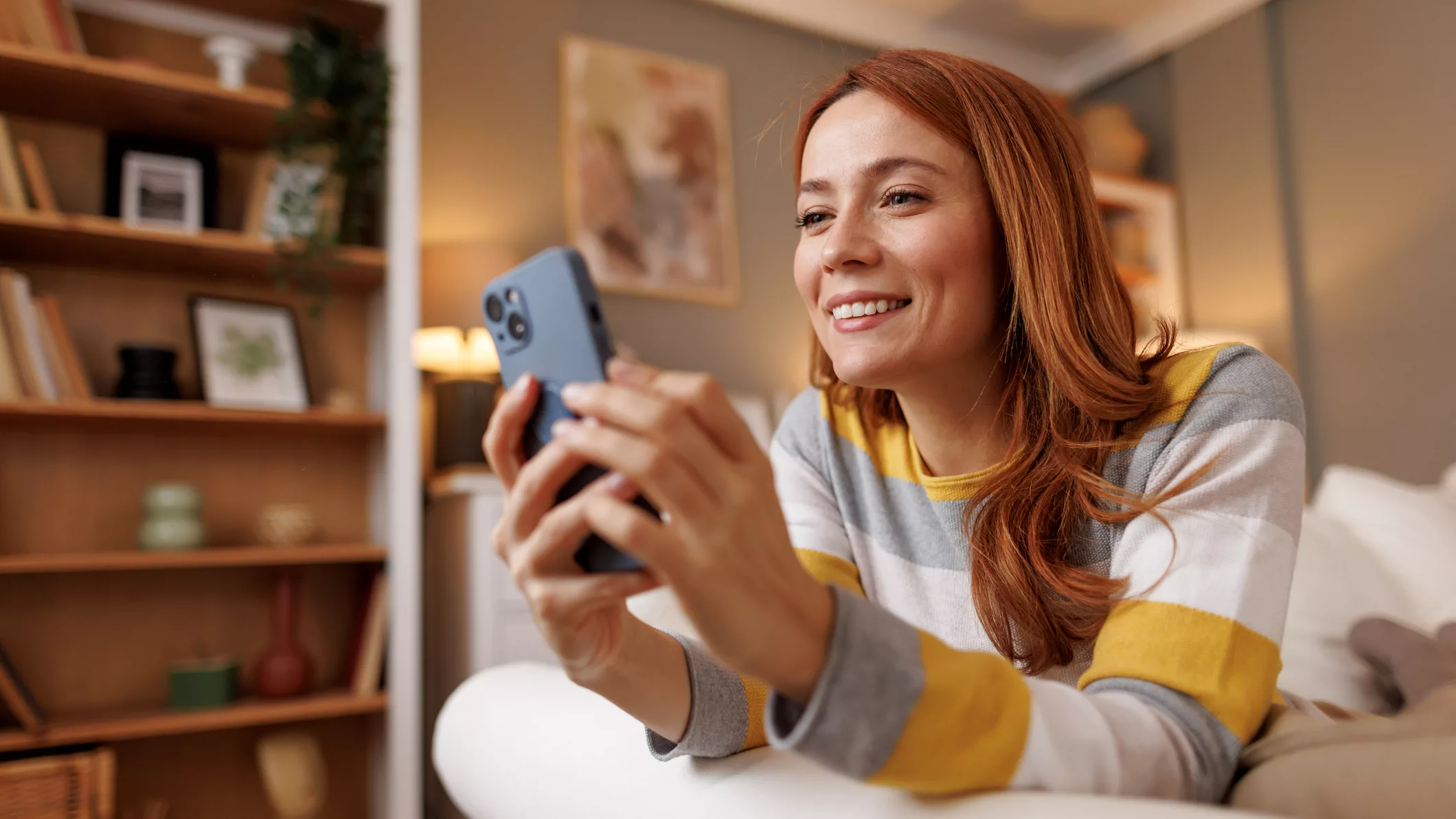 Junge Frau mi Smartphone auf dem Sofa