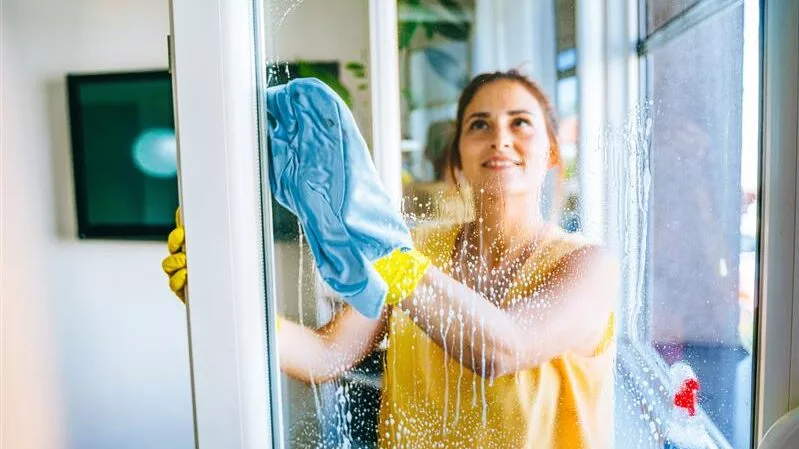 Frau putzt Fenster