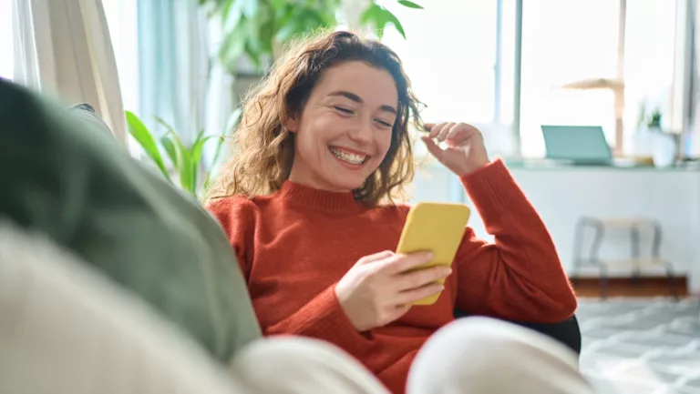 Junge Frau mi Smartphone auf dem Sofa