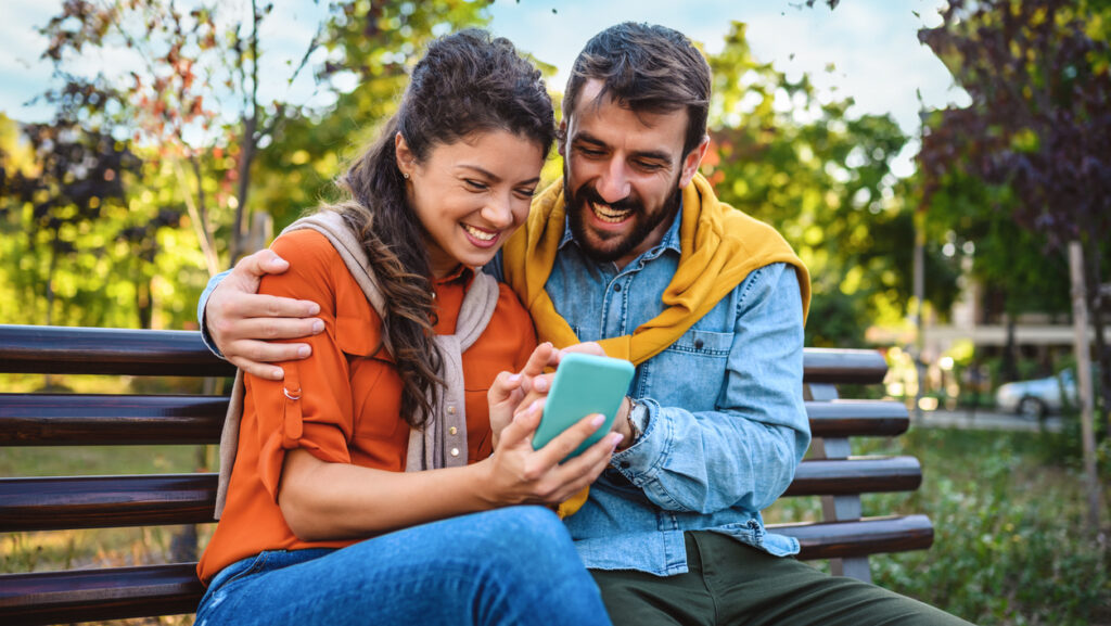 Paar auf einer Bank mit Handy in der Hand.