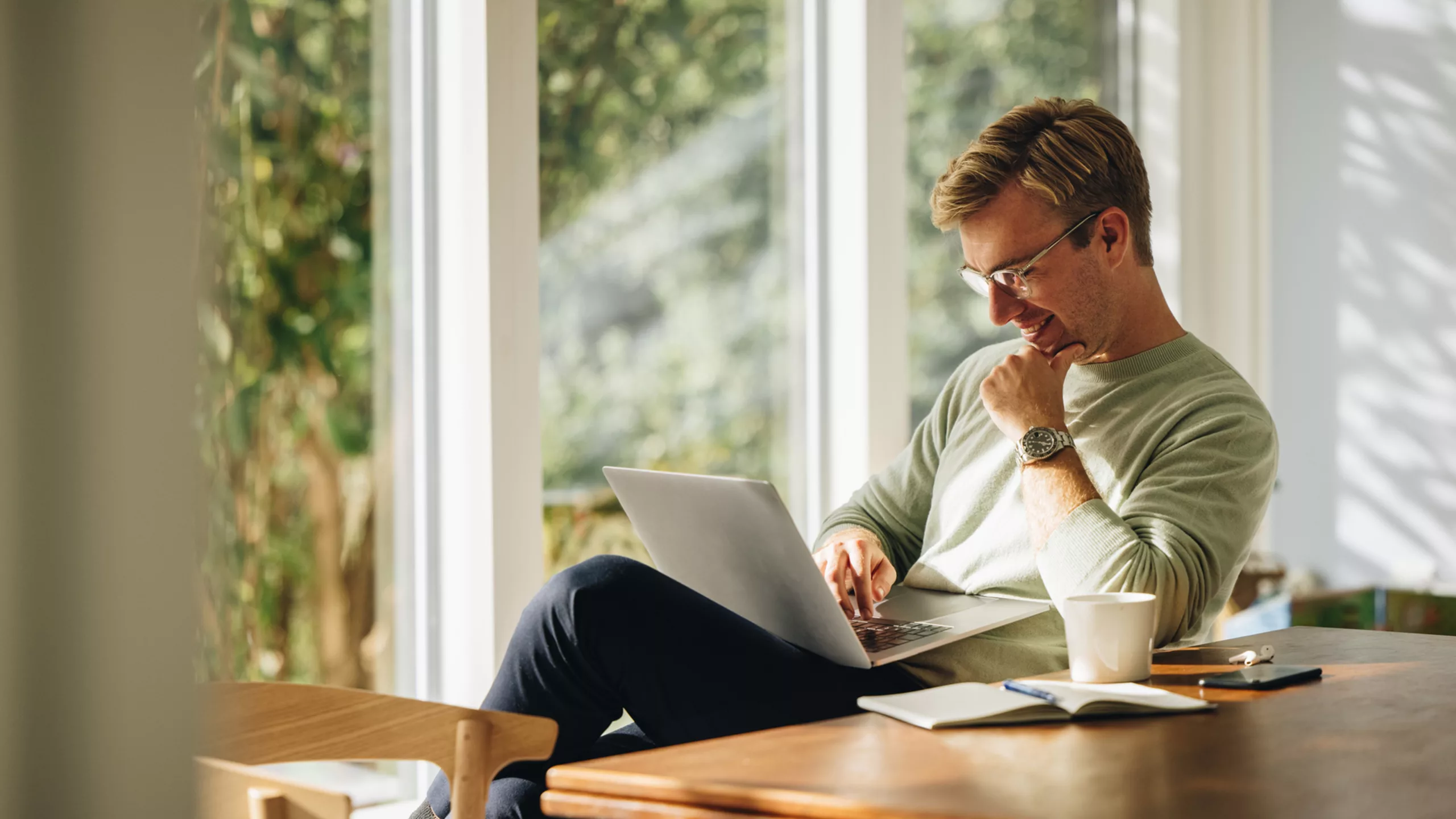 Junger Mann schaut lachend auf seinen Laptop in seinem Wohnzimmer. (@istockphoto.com)