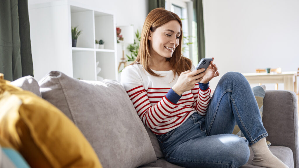 Frau auf dem Sofa mit Handy.