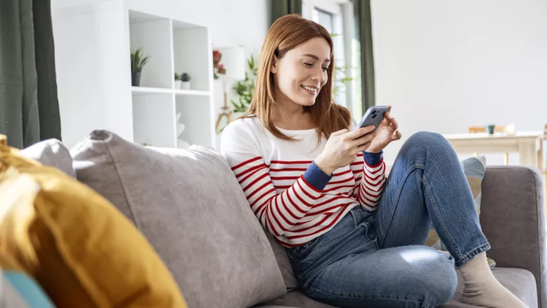 Frau auf dem Sofa mit Handy.