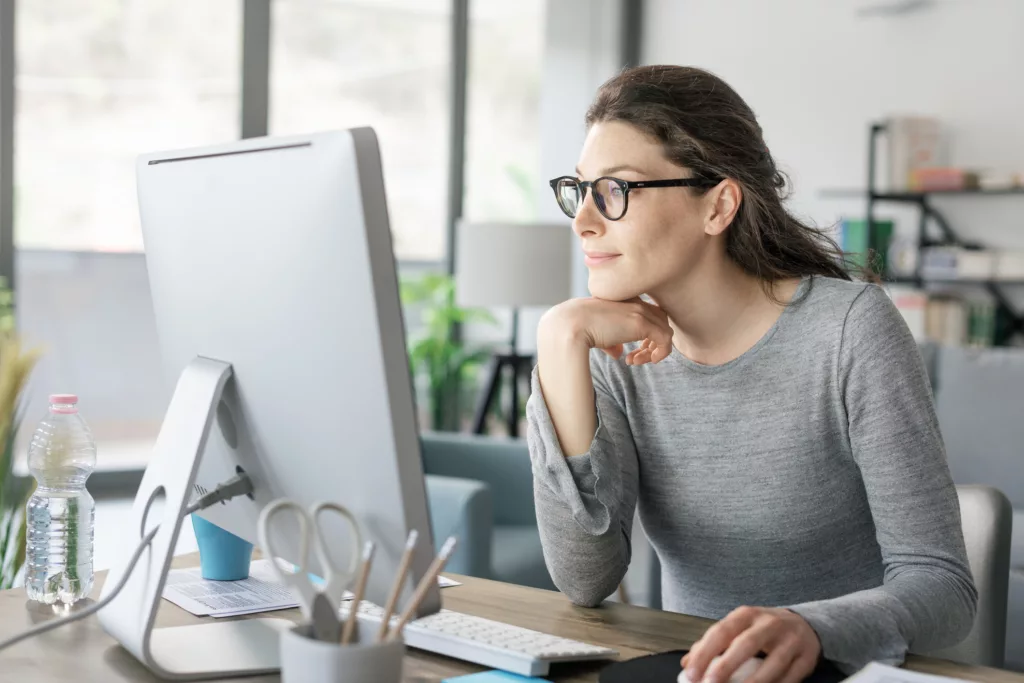 Eine Frau arbeitet am Computer und sieht zufrieden aus (@istock)
