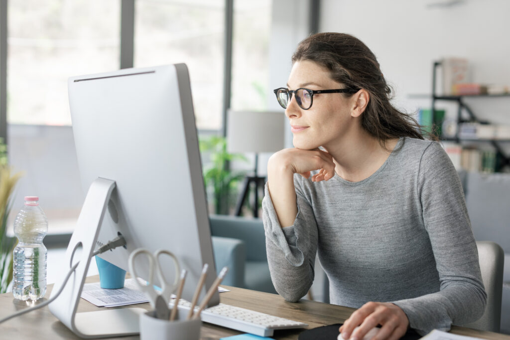 Eine Frau arbeitet am Computer und sieht zufrieden aus (@istock)