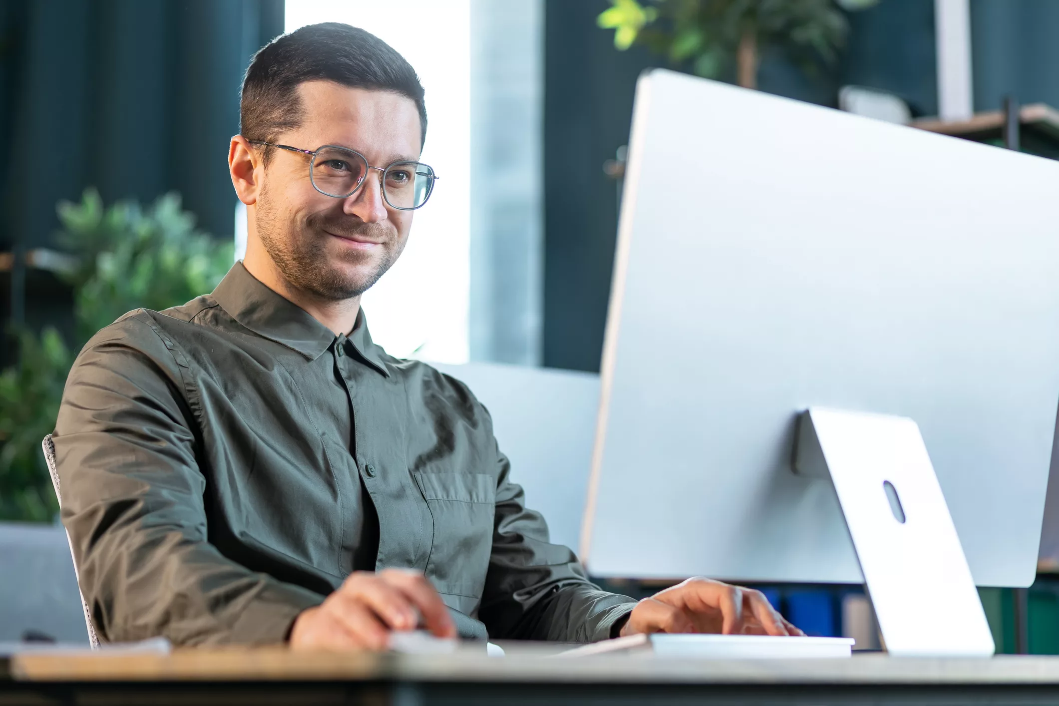 Ein Mann im Business-Dress guckt souverän auf einen Bildschirm und grinst (@istockphoto / Ivan Kyryk)