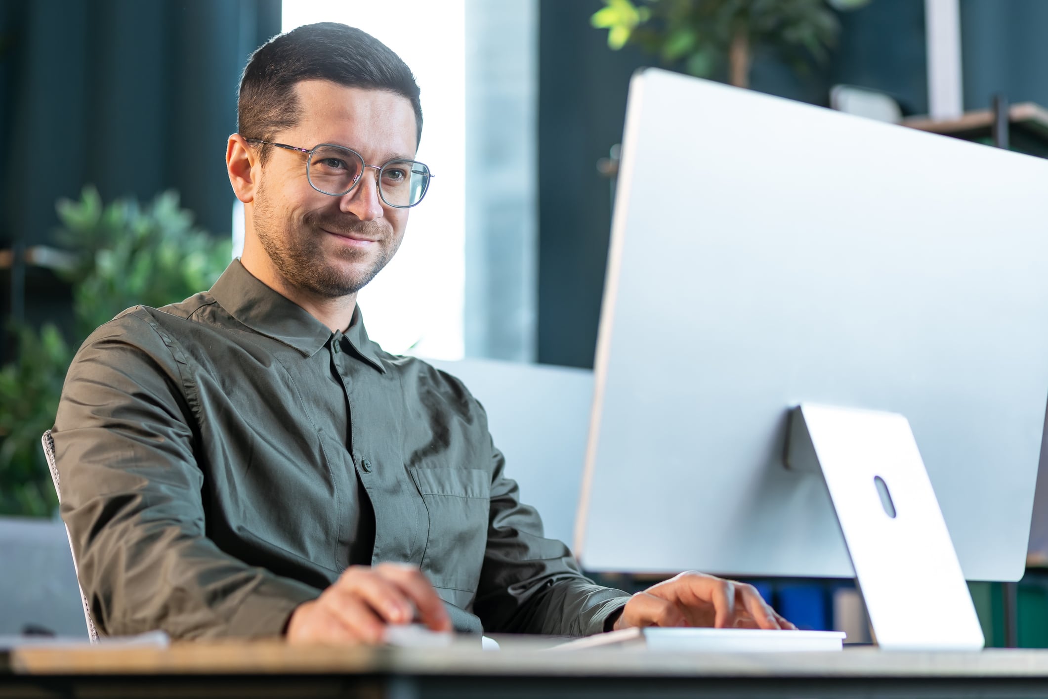 Ein Mann im Business-Dress guckt souverän auf einen Bildschirm und grinst (@istockphoto / Ivan Kyryk)