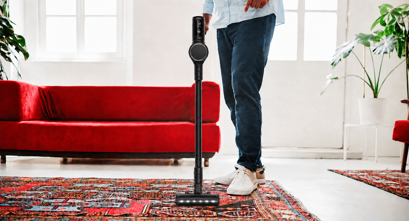 Mann saugt Teppich mit dem CHIP Akku-Staubsauger in einem Wohnzimmer.