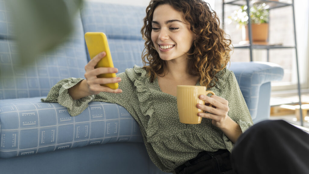 Frau vor dem Sofa mit Handy.