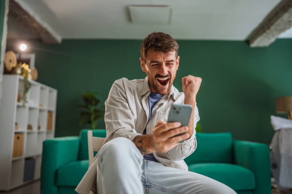 Mann mit Smartphone freut sich