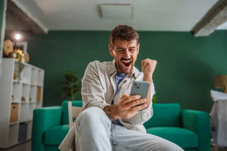 Mann mit Smartphone freut sich