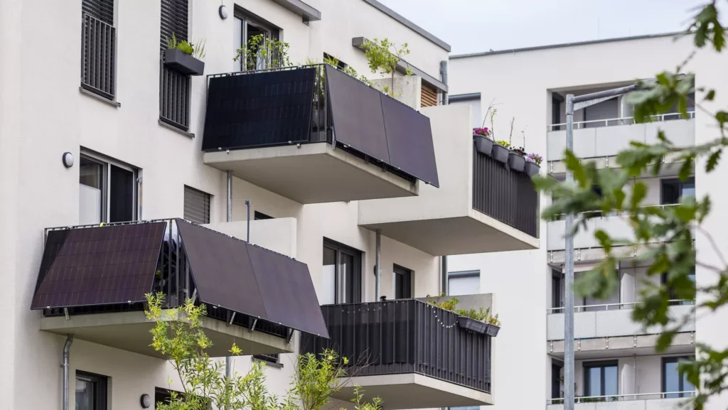 Dunkle Solarpanels von Balkonkrafwerken an den Balkonen weißer Mehrfamilienhäuser (@istock)