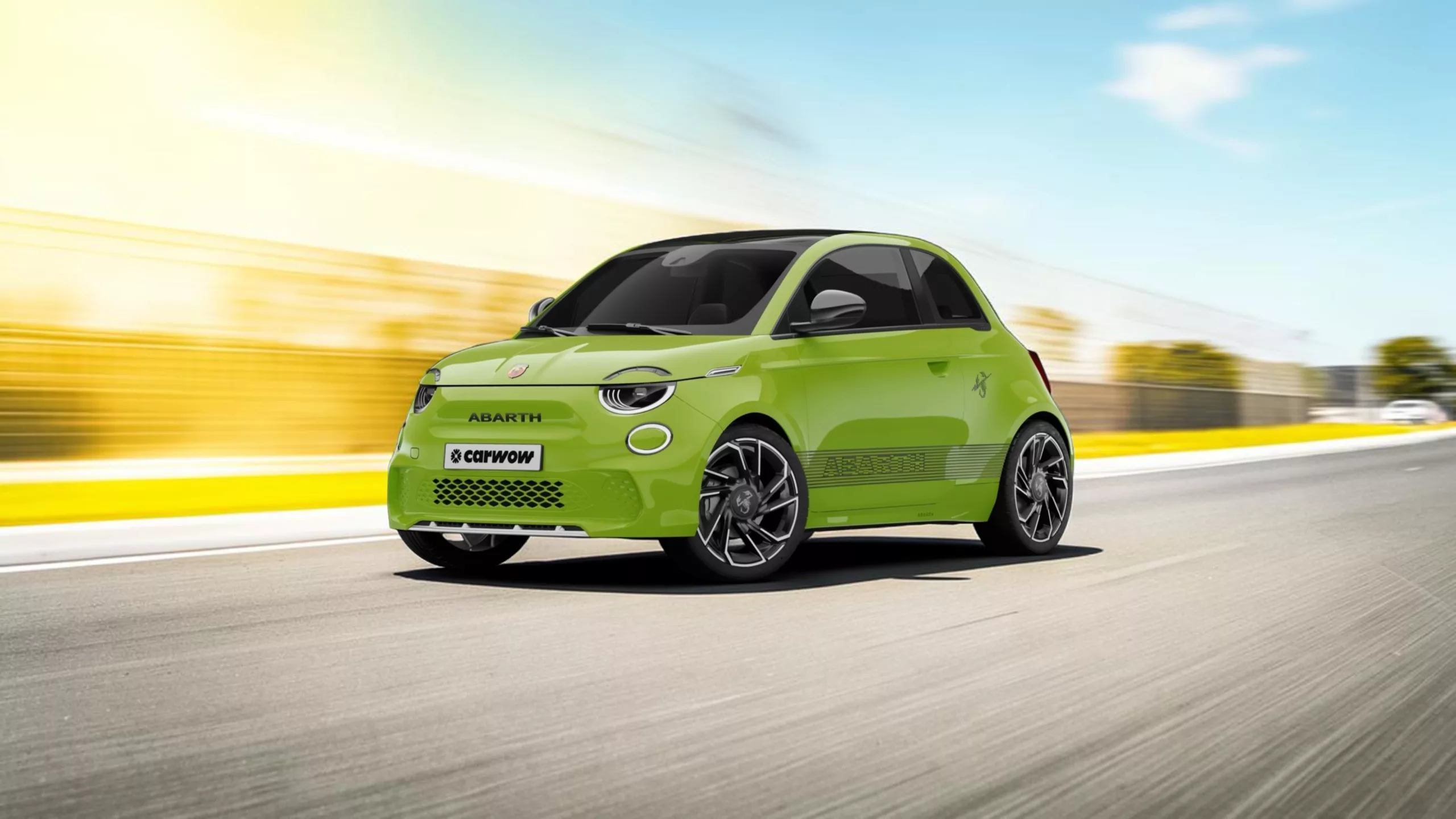 Grünes kleines rundliches Auto von Abarth schräg von der Seite auf Straße mit Gelb blauem Hintergrund angedeuteten verschwommenen Häusern