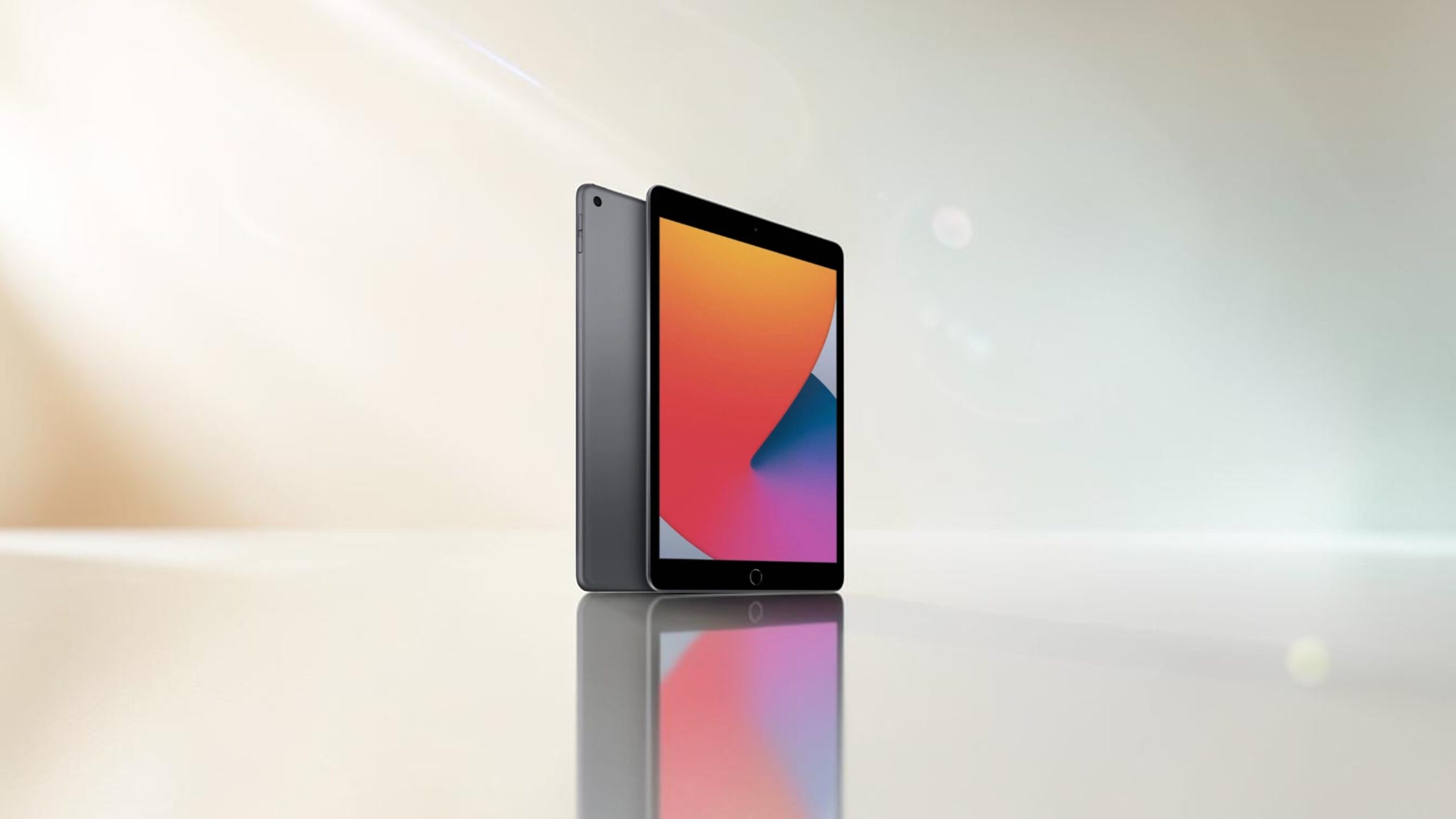 Graues Apple iPad Tablet schräg von der Seite von hinten und vorne mit bunten Farben auf Display auf einer spiegelnden Fläche gold blaugraue Farbverläufe und Lichtreflexionen im Hintergrund