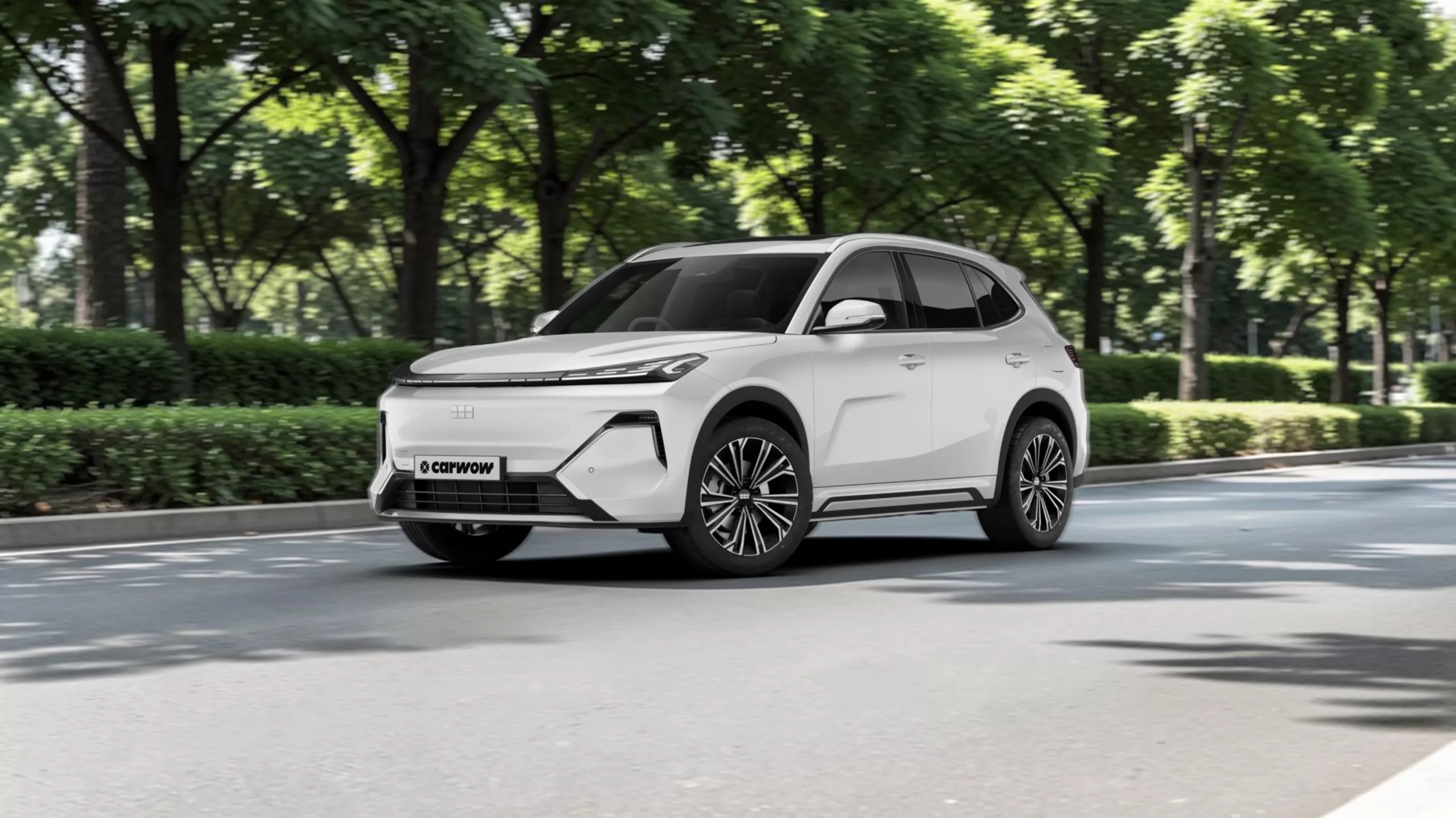 Weißes Auto SUV von Geely schräg von der Seite auf Straße vor grünen Bäumen und Büschen