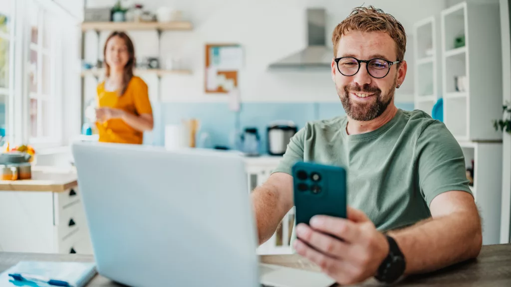Mann mit Smartphone und Laptop