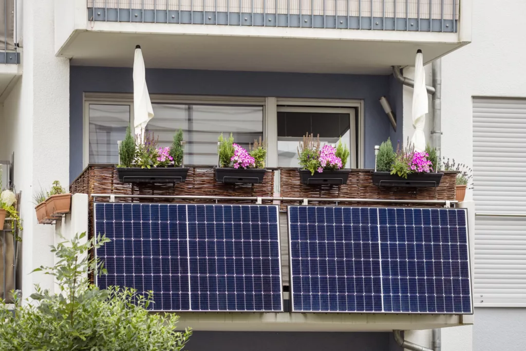 Solarpanels an einem Balkon eines Mehrfamilienhauses, Blumenkästen sind darüber sichtbar. (@istock)
