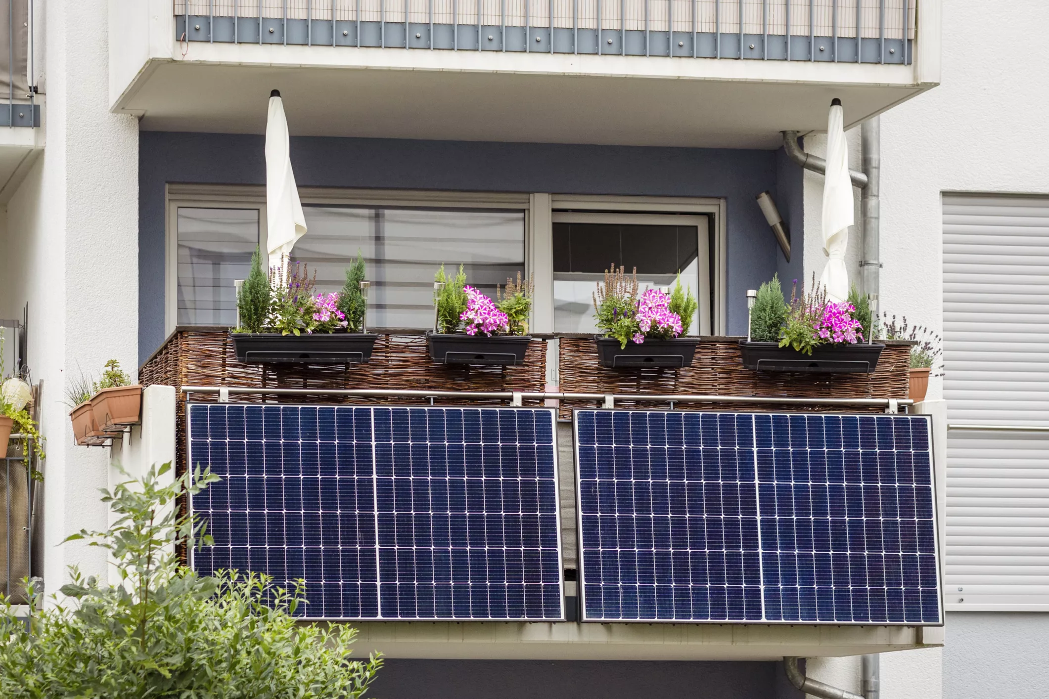 Solarpanels an einem Balkon eines Mehrfamilienhauses, Blumenkästen sind darüber sichtbar. (@istock)