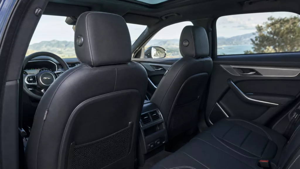 Rückbank vom Jaguar F-Pace in schwarz verkleidet, mit bergiger Küstenlinie draußen im Hintergrund