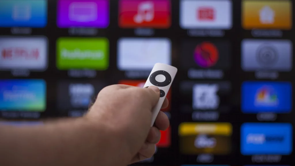 Hand zeigt mit Fernbedienung auf ein Smart-TV