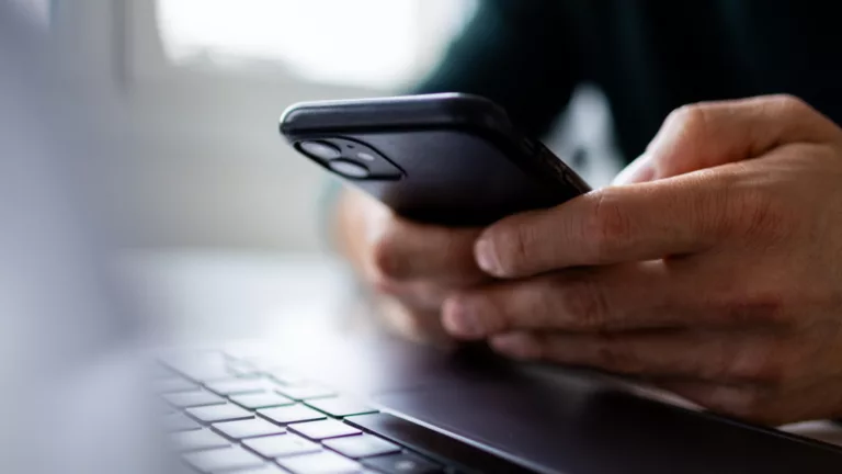 Mann mit Smartphone und Laptop.