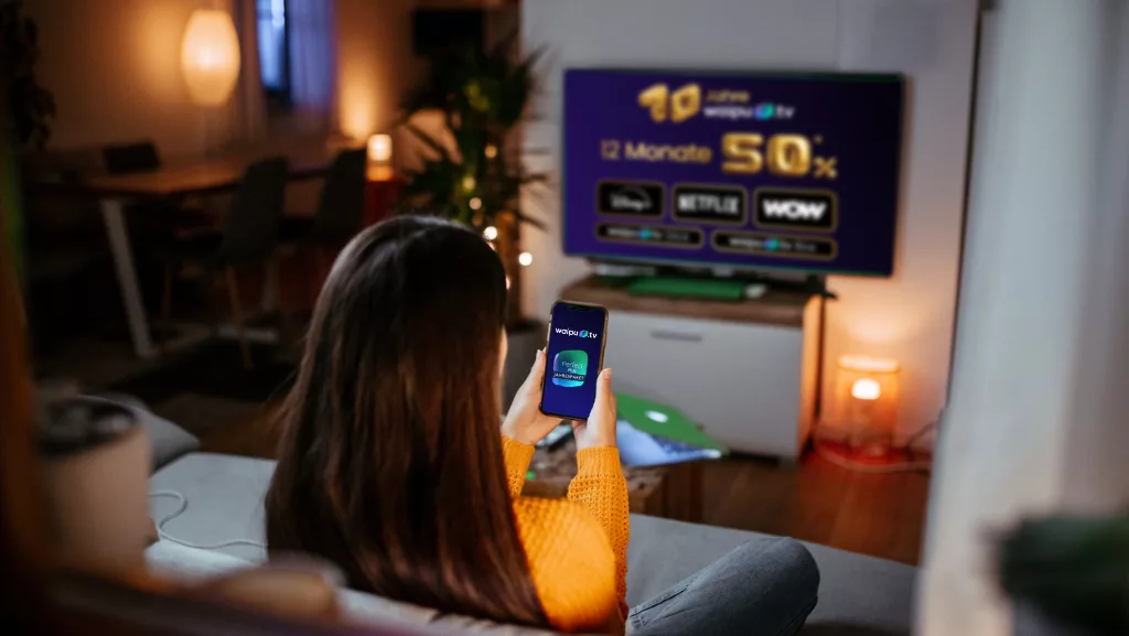 Frau auf Couch guckt Waipu.tv