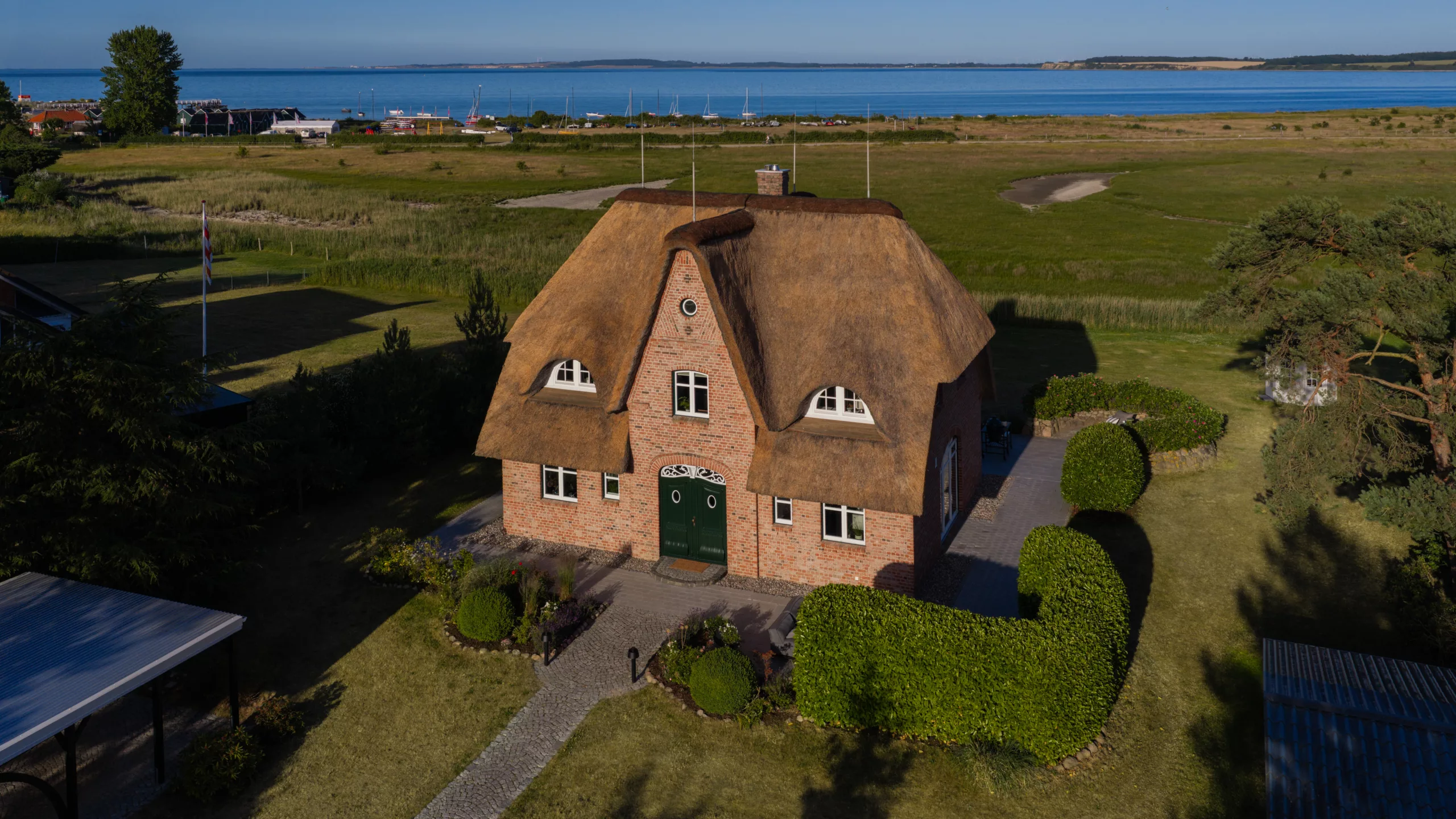 Haus mit Reetdach von oben in grüner Landschaft Küste oben zu sehen