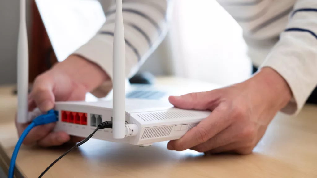 Person steckt Kabel in einen Router