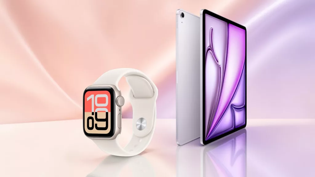 Helle Apple Watch schräg von der Seite im Vordergrund, im Hintergrund hochkant aufgestelltes iPad hell vor rosa und lila Hintergrund